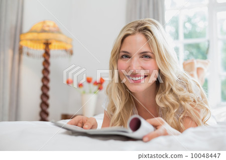 Beautiful casual woman reading magazine in bed Beautiful casual woman reading magazine in bed 10048447