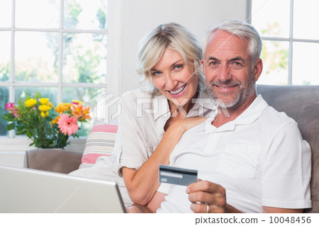 Happy mature couple doing online shopping at home Happy mature couple doing online shopping at home 10048456