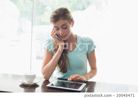 Woman with coffee cup using digital tablet and cellphone in coff 10048471