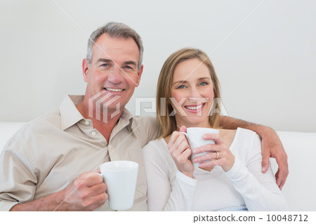 Relaxed loving couple with coffee cups in living room 10048712