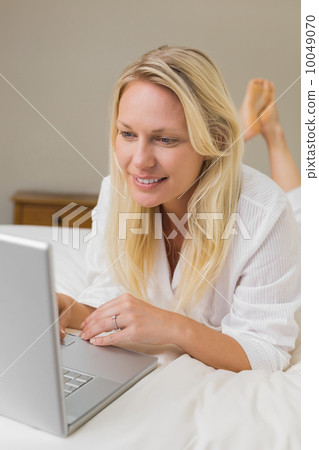 Blond woman using laptop in bed 10049070
