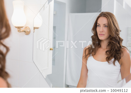 Woman looking at herself in the bathroom mirror 10049112