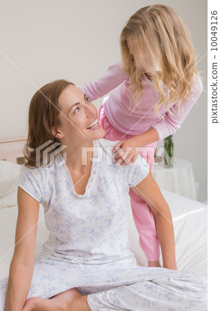Happy woman and girl playing in bedroom Happy woman and girl playing in bedroom 10049126