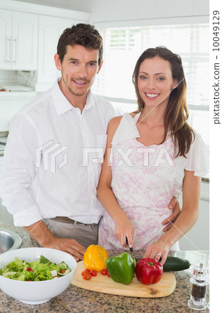 Portrait of a couple cutting vegetables in kitchen Portrait of a couple cutting vegetables in kitchen 10049129