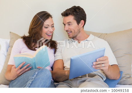 Happy couple with laptop and book on couch Happy couple with laptop and book on couch 10049158