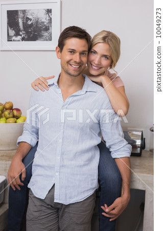Smiling woman embracing man from behind at home Smiling woman embracing man from behind at home 10049273