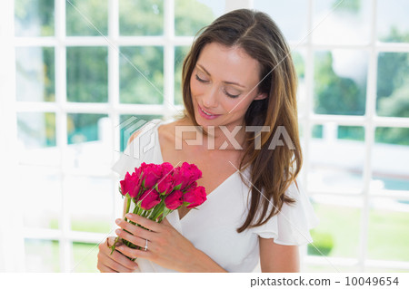 Thoughtful woman with flowers at home Thoughtful woman with flowers at home 10049654