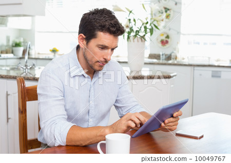 Concentrated man using digital tablet in kitchen 10049767