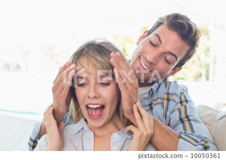 Man surprising woman in living room 10050361