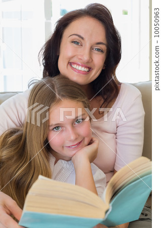 Woman and daughter with book at home 10050963