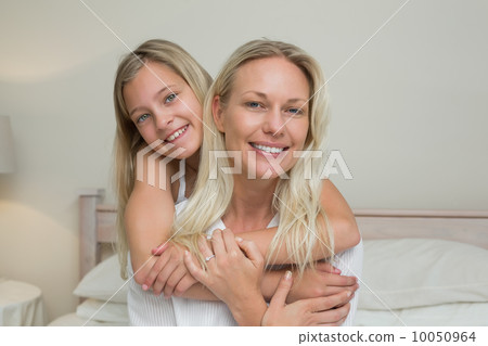 Girl embracing mother from behind in bed Girl embracing mother from behind in bed 10050964