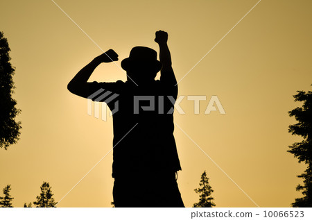 夕陽餘暉中,一個男人擺出勝利姿勢的剪影。 夕陽餘暉中,一個男人擺出勝利姿勢的剪影。 10066523
