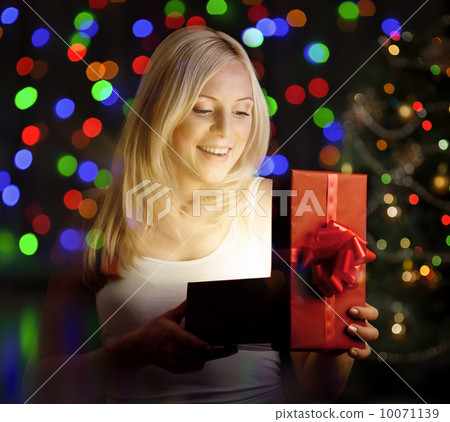 Young woman opening  gift box in front of christmas tree 10071139