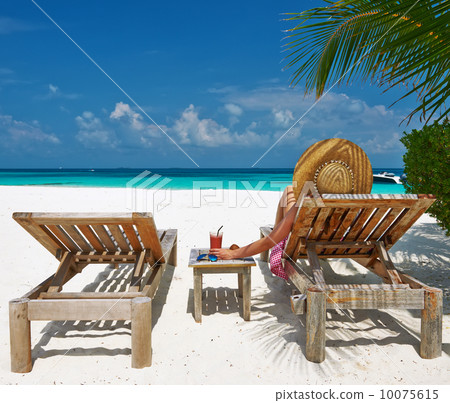 Woman at beach with chaise-lounges 10075615