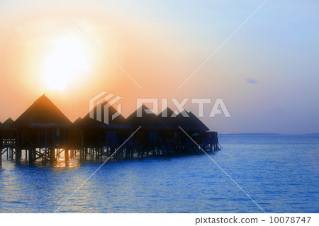Maldives. .Villas on water in beams of sunset sun, soft focus 10078747