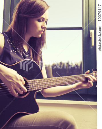 Playing acoustic guitar by the window Playing acoustic guitar by the window 10079147