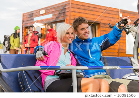 Cheerful couple sitting chair lift man pointing Cheerful couple sitting chair lift man pointing 10081506