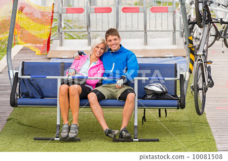 Cuddling couple sitting chair lift with bicycles Cuddling couple sitting chair lift with bicycles 10081508