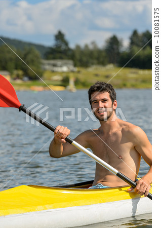 Smiling sporty man kayaking on lake 10081575