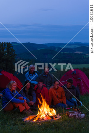 In dark camper friends sitting around fire In dark camper friends sitting around fire 10081611