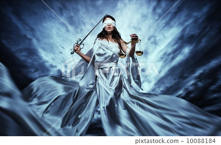 Femida, Goddess of Justice, with scales and sword wearing blindfold against dramatic stormy sky 10088184