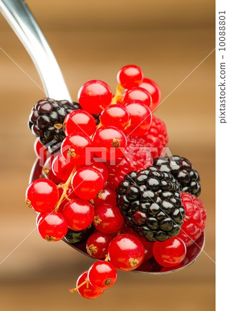 Fresh berries on a spoon against wooden background 10088801