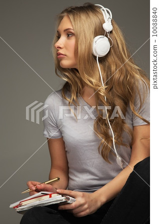 Young woman student with notebook listens to music 10088840