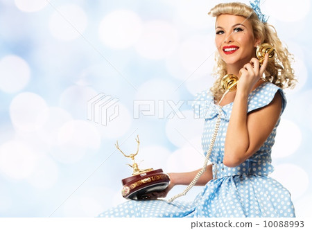 Coquette blond pin up style young woman in blue dress with vintage phone 10088993
