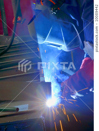 welder with protective mask welding metal and sparks 10089442