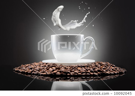 white cup with coffee beans and milk splash on black 10092045