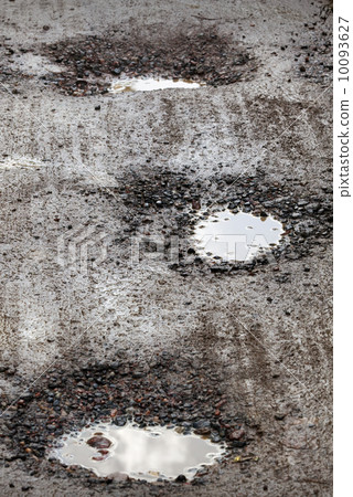 Damaged wet road with holes Damaged wet road with holes 10093627