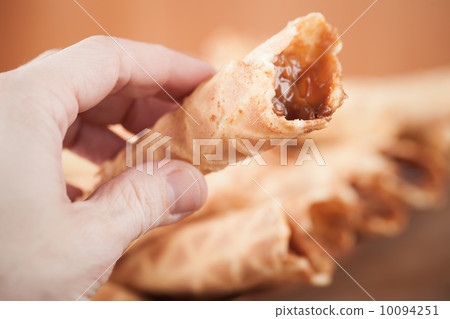 Homemade wafer cone with cream of sweet boiled condensed milk in man's hand. Traditional Russian dessert 10094251