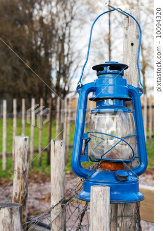 Blue vintage kerosene lamp hangs on wooden outdoor fence Blue vintage kerosene lamp hangs on wooden outdoor fence 10094320