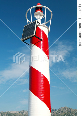 Red and white striped lighthouse above cloudy sky. Perast town, 10094813