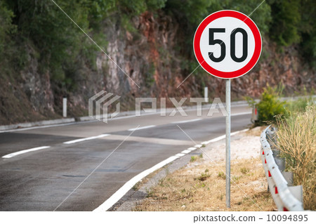 Round speed limit road sign on mountain road Round speed limit road sign on mountain road 10094895