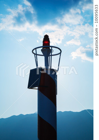 Small red lighthouse lantern above dark blue cloudy sky 10095633