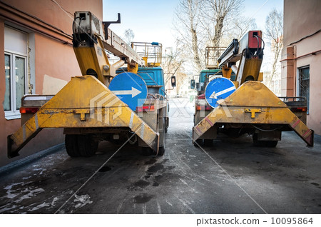Two yellow supply service trucks with arrows on blue signs 10095864