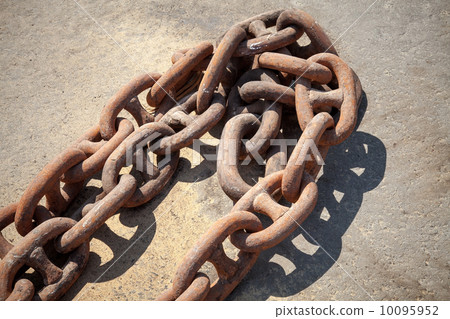 Rusty ship anchor chain on dry coast in the port 10095952