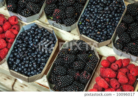 Different berries lay on the counter in paper boxes Different berries lay on the counter in paper boxes 10096017
