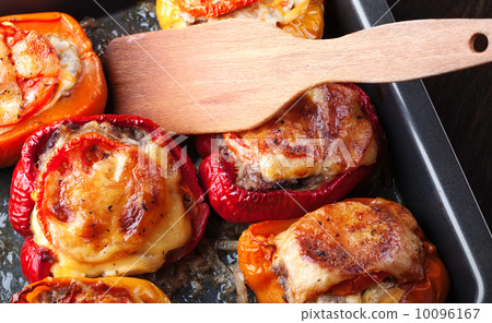 Stuffed bell peppers with chopped meat, cheese and tomato on black baking pan Stuffed bell peppers with chopped meat, cheese and tomato on black baking pan 10096167
