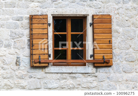 Wooden window with open jalousies in old gray stone wall 10096275