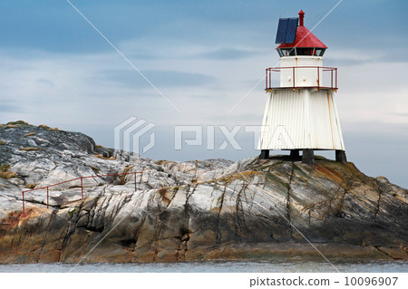 Traditional Norwegian lighthouse. White tower on rocky island with solar battery and red top Traditional Norwegian lighthouse. White tower on rocky island with solar battery and red top 10096907