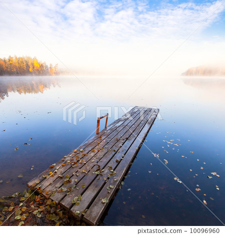 Small wooden pier on still lake in bright autumnal foggy morning Small wooden pier on still lake in bright autumnal foggy morning 10096960