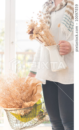 一位婦女將乾燥花放入籃子裡。 10097859