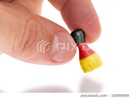 Hand holding wooden pawn, flag painting, selective focus Hand holding wooden pawn, flag painting, selective focus 10099999