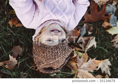 Very cheerful child having fun while tossing up  leaves 10116678