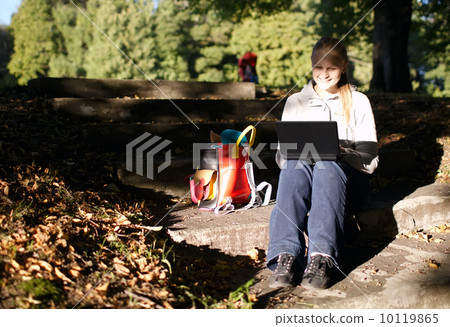 Young woman working outdoors on a laptop 10119865