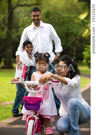 indian family teaching their kids cycling in the outdoor park 10122029