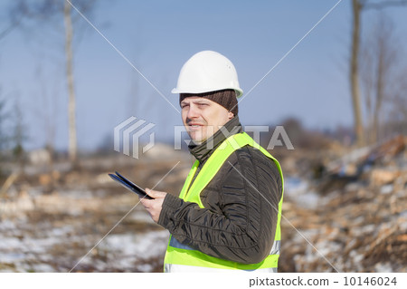 Lumberjack with tablet PC in cleared forest in winter 10146024