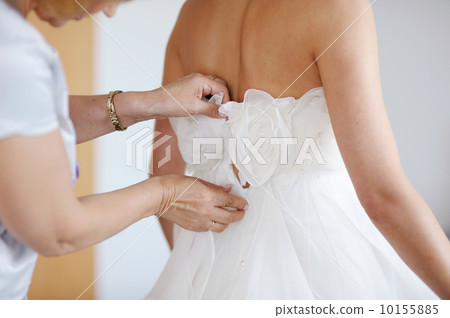 Helping the bride to put her wedding dress 10155885